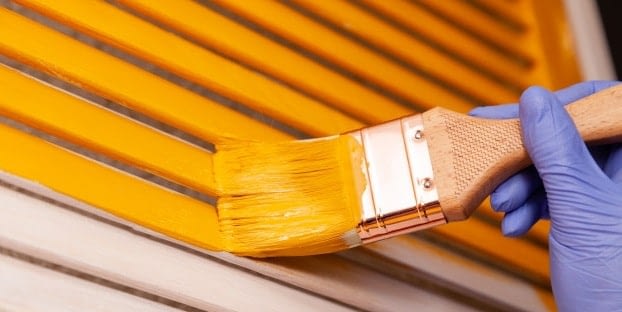A Man Painting A Door Using A Brush